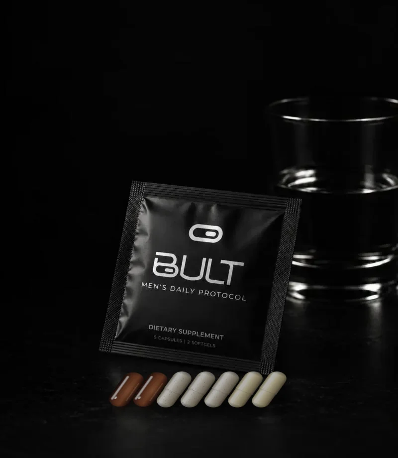 A BULT pouch beside a glass of water, with its 2 softgels and 5 capsules lined up in front